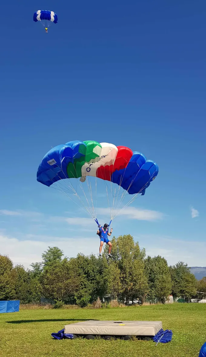 Paracadutista con vela multicolore in avvicinamento al bersaglio di atterraggio