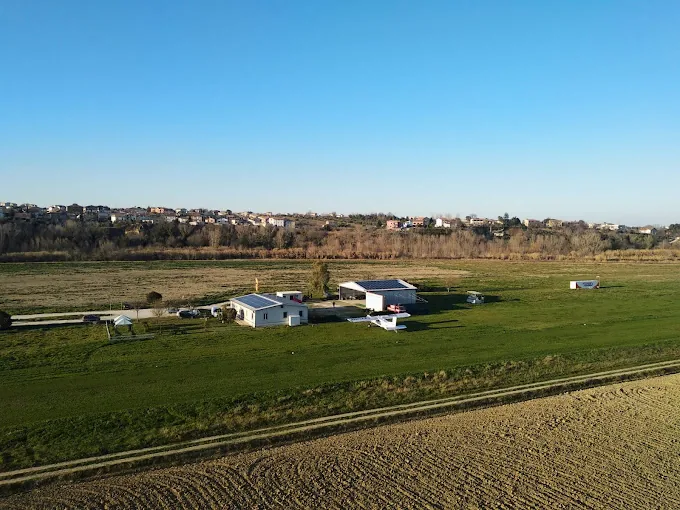 Veduta aerea dell'Aviosuperficie del Fermano con pista in erba, hangar e velivoli