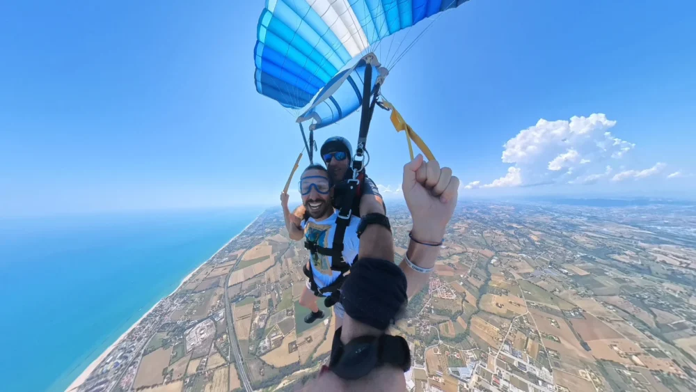 Passeggera durante il volo con paracadute tandem aperto sopra le Marche