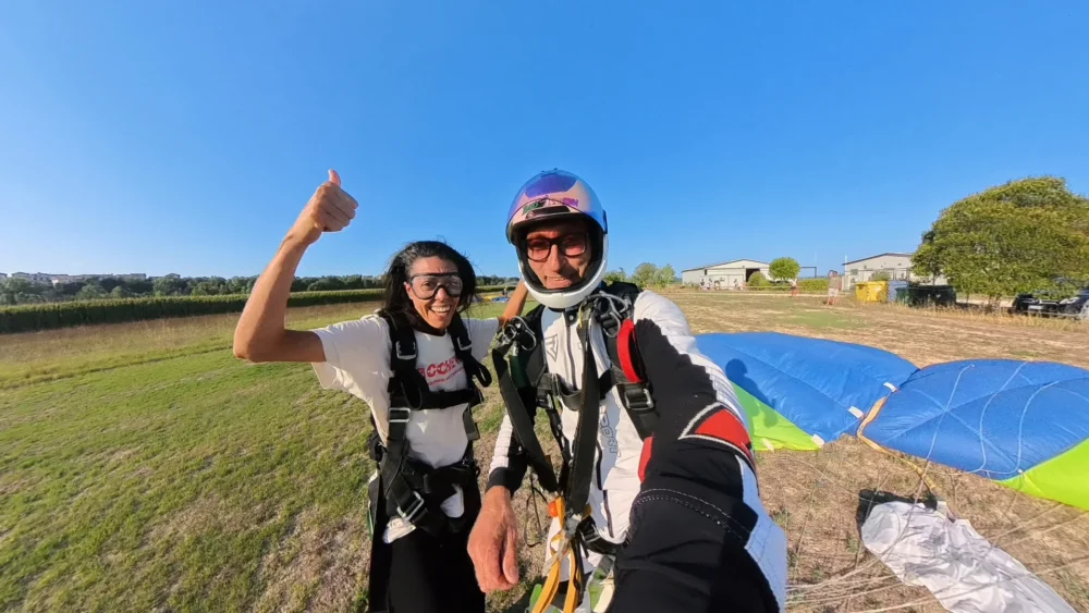 Passeggera e istruttore sorridenti dopo l’atterraggio tandem con la vela sul campo