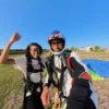 Passeggera e istruttore sorridenti dopo l’atterraggio tandem con la vela sul campo
