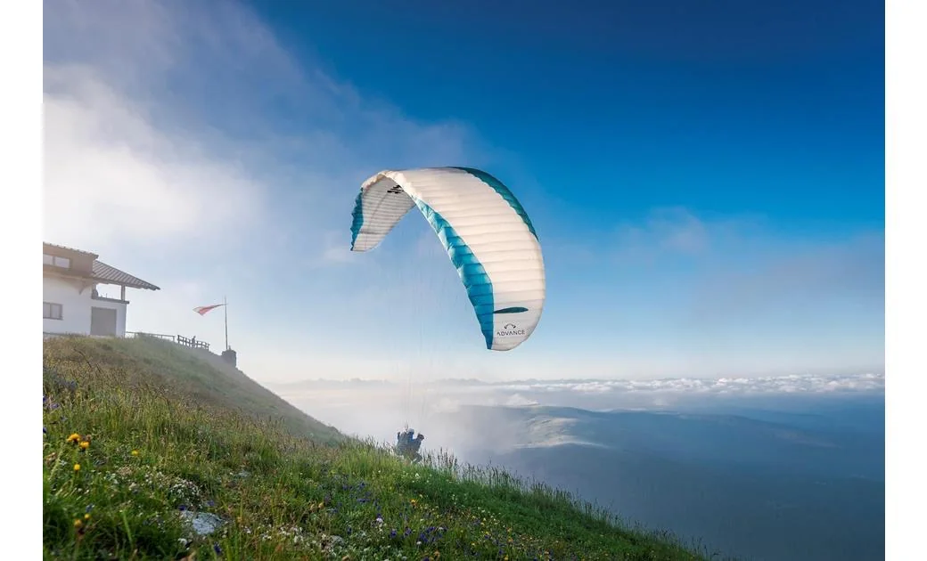 Parapendio in volo sopra un pendio di montagna con la vela già aperta