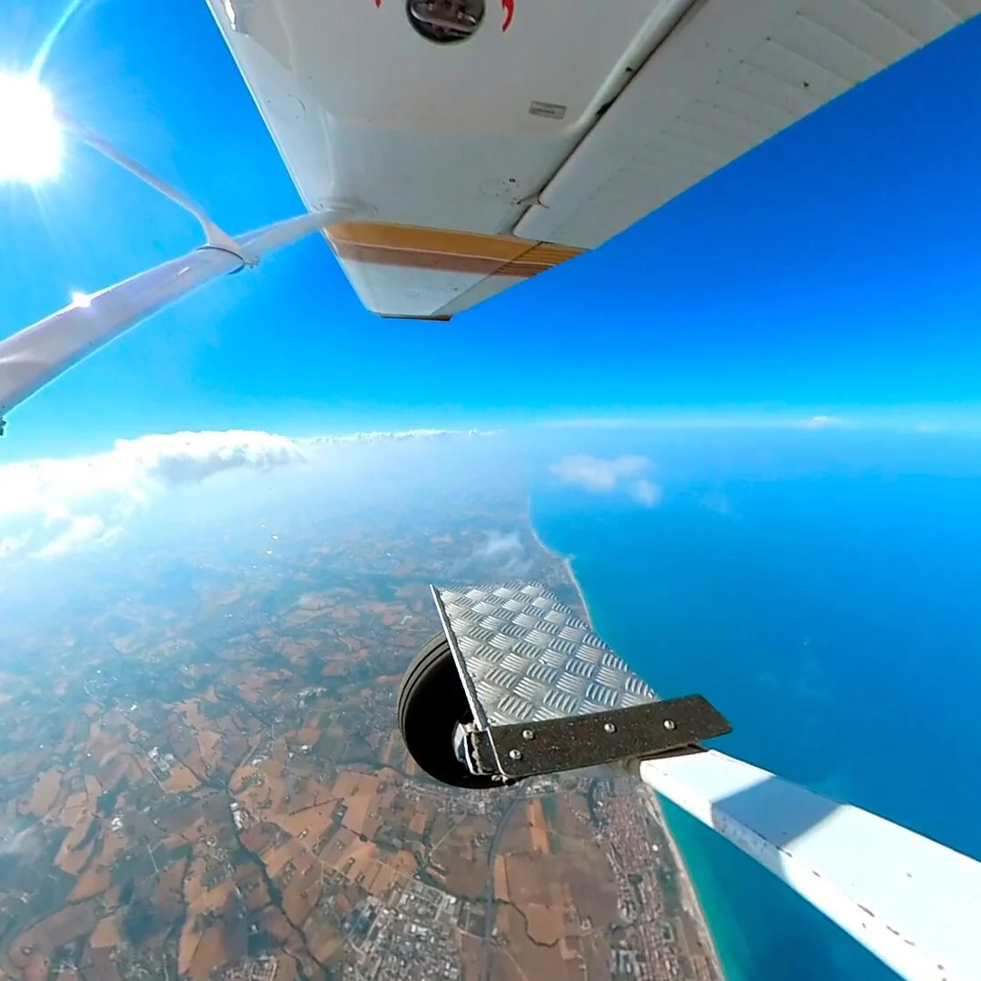 Vista dal portellone aperto dell’aereo con predellino e paesaggio sottostante durante la salita in quota